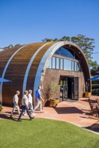 A group walking past a wine barrel building on a scenic Cheese and Wine Day Tour in the Sunshine Coast Hinterland.